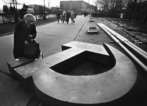 A woman reaches into her bag, which rests on a fallen Soviet hammer-and-sickle on a Moscow street in 1991, Getty Images