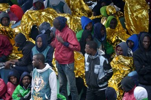 Migrants wait at a Lampedusa holding center. (Click image for source)