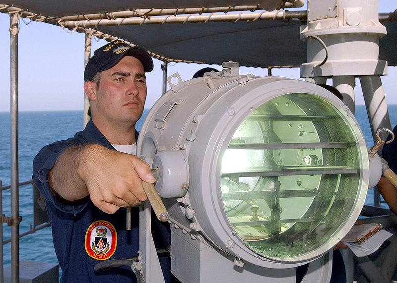 800px-US_Navy_020623-N-5329L-007_Signalman_2nd_Class_Eric_Palmer_signals_the_U.S._Navy_mine_hunter_coastal_ship_USS_Raven_%28MHC_61