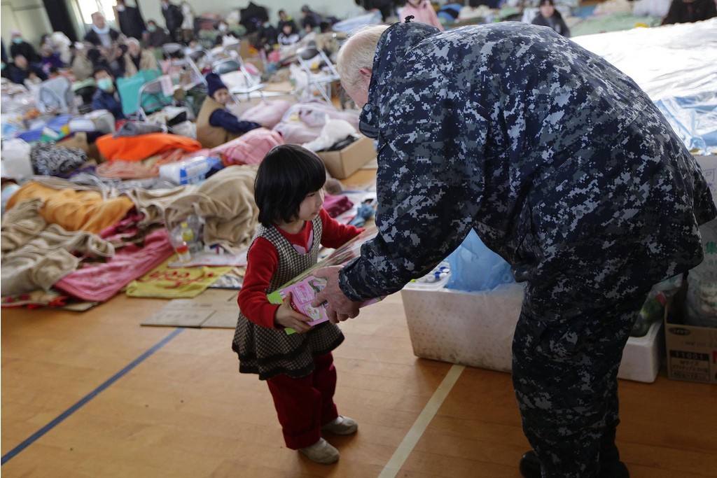 Navy Adm. Robert F. Willard, commander of U.S. Pacific Command, gives a toy to a child while touring a shelter facility in Ishinomaki city, Miyagi Prefecture, Japan, March 23. Willard and John V. Roos, U.S. ambassador to Japan, assisted in the delivery of relief supplies to displaced citizens. Since March 12, Marines and sailors have delivered food, fuel, water and supplies to disaster-stricken areas near Sendai as part of Operation Tomodachi. (Photo by: Lance Cpl. Steve Acuff)