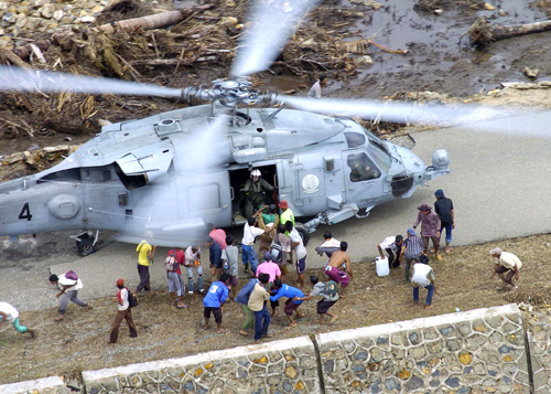 Indonesians from the village of Tjalang, Sumatra, Indonesia, rush towards a SH-60 Seahawk helicopter, assigned to Helicopter Anti-Submarine Squadron 2, as the helicopter touches down to drop off food supplies, Jan. 8, 2005. Helicopters assigned to Carrier Air Wing 2 and sailors from the aircraft carrier USS Abraham Lincoln are supporting Operation Unified Assistance, the humanitarian effort in the wake of the tsunami that struck Southeast Asia. (U.S. Navy photo by Petty Officer 2nd Class Philip A McDaniel)