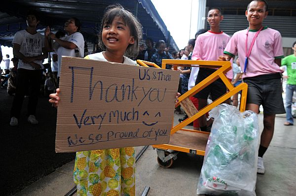 111023-N-WW409-696 UTAPAO, Thailand (Oct. 23, 2011) A child from the local community holds a sign thanking the U.S. Sailors from the guided missile destroyer USS Mustin (DDG 89) and members from the Royal Thai Armed Forces during a community service event organized by the Princess Pa Foundation, Thai Red Cross Society. More than 40 Sailors from Mustin volunteered their time with the local community and members from the Royal Thai Armed Forces with assisting in preparing more than 5,000 packages. (U.S. Navy photo by Mass Communication Specialist 1st Class Jennifer A. Villalovos/Released)