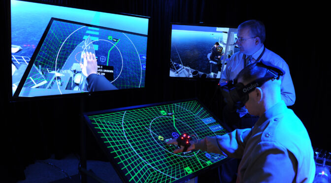 Jim Blesse, standing, from the Office of Naval Research, explains project BlueShark to Lt. Col. John Moore from the Marine Corps Warfighting Laboratory. Project BlueShark is an ONR effort to create a high-tech, futuristic environment to demonstrate what operational work environments might look like and what emerging innovative technologies might provide in the next decade. (U.S. Navy photo by John F. Williams/Released)